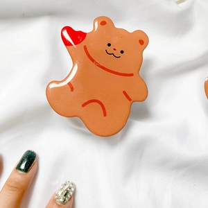 Close-up of cute brown bear acrylic phone grip with resin finish and red heart detail