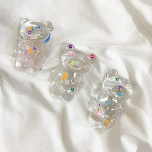 Detail of three transparent acrylic bear phone grips with colorful floral and heart patterns