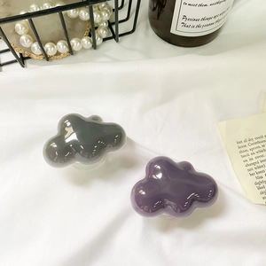Close-up of glossy cloud-shaped phone grips in dark purple and grey on white fabric