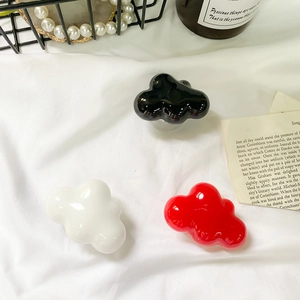 Close-up of cloud-shaped expanding phone grips in black, white, and red on satin