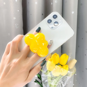 Detailed view of a bright yellow cloud-shaped resin phone grip on a white case
