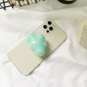 Detailed view of a mint green cloud-shaped glossy resin phone socket on a white fabric background