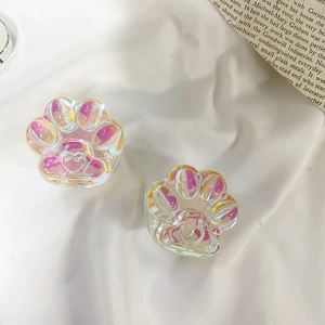 Close-up of cat paw holographic phone socket grips on a white fabric background