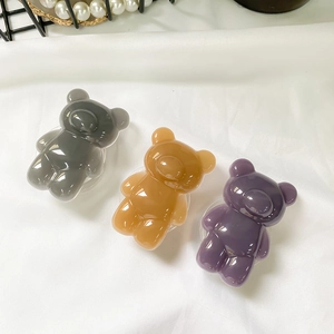 Macro shot of 3D resin bear phone sockets in amber, grey and purple on white fabric