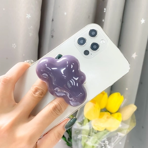 Detailed view of glossy purple cloud-shaped phone grip attached to a white smartphone