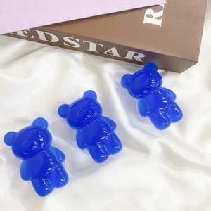 Detailed view of three blue translucent bear phone grip stands on white fabric background
