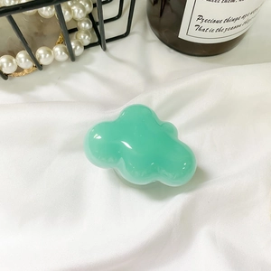 Detail shot of mint green cloud-shaped phone grip with glossy 3D finish on white fabric