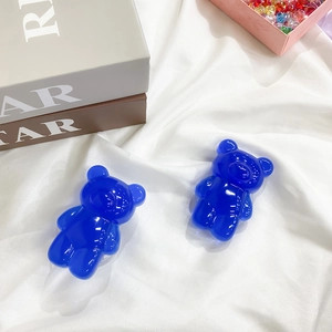 Close-up of translucent blue gummy bear phone grips set on a white fabric background