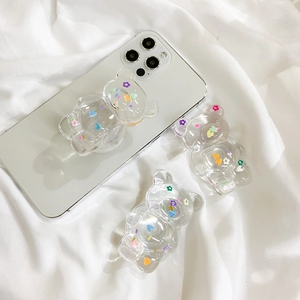 Transparent bear phone grip with colorful heart and flower patterns on white smartphone