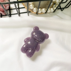Detail of purple translucent resin bear phone grip on elegant white fabric background