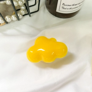 Detailed close-up of glossy bright yellow cloud-shaped phone socket on white fabric