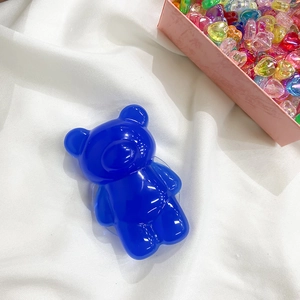 Detail view of blue translucent bear phone grip on white textured fabric background