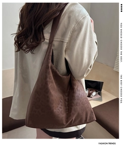 Detail of a large brown suede tote bag with leopard print shown on a shoulder