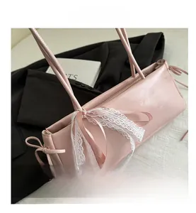 Close-up of pink baguette bag featuring sweet white lace bow and side drawstring details