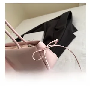 Detail of pink leather handbag featuring a decorative side bow and smooth zipper closure