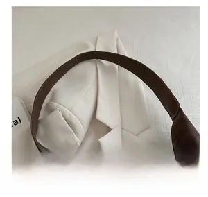 Close-up of the comfortable wide handle and leather texture on a dark brown handbag