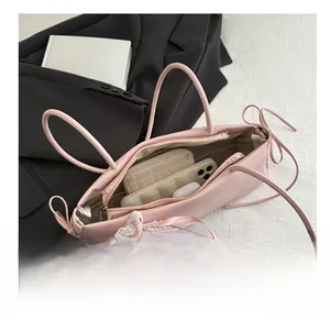 Pink baguette bag with bow and lace detail showing internal storage for phone and wallet
