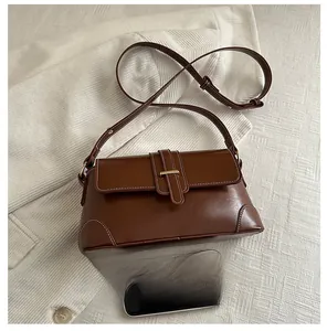 Detailed view of brown baguette bag with contrast stitching and size comparison to phone