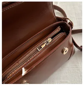 Detail view of smooth zipper and inner compartment of brown faux leather crossbody bag