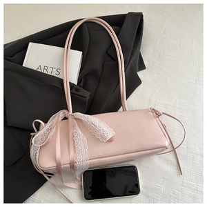 Detailed view of pink baguette bag with white lace trim and ribbon bow on white fabric