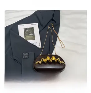 Micro-sized dark brown chain evening bag with bold gold wavy metal accent and slim strap