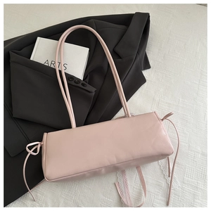 Detailed view of light pink rectangular underarm bag with decorative drawstring bows