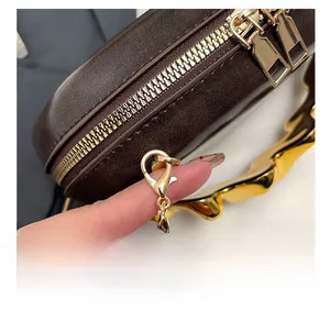 Detail show of golden dual-zipper closure and wavy metal handle on brown leather handbag
