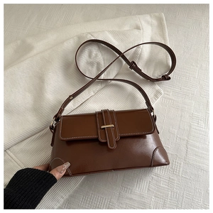 Detail of dark brown leather handbag showing white contrast stitching and gold buckle