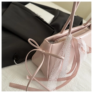 Detailed shot of pink ballet-style bag featuring white lace trim and silk bow decoration