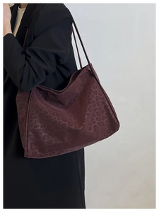Detail of a large leopard print tote bag in dark plum fabric worn over the shoulder