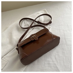Macro detail of brown leather bag showing white contrast stitching and metal buckle