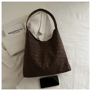 Detailed overhead shot of leopard print tote bag on white texture with fashion accessories