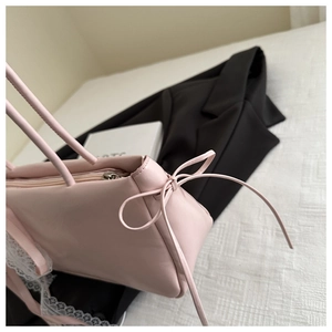 Detailed view of pink faux leather bag with bow tie ribbon and white lace trim