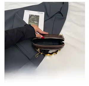 Detail showing the inner storage space and gold wave handle of the brown leather bag