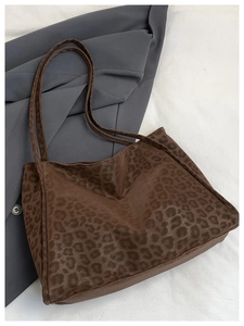 Detailed top view of a large leopard print tote bag styled with a grey blazer coat