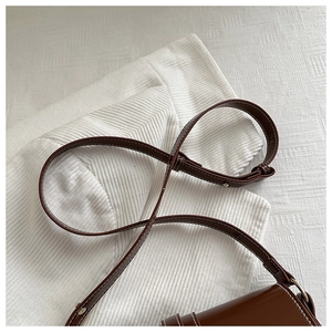 Detailed close-up of brown leather bag strap featuring white contrast stitching and metal buckle