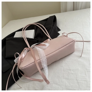 Close-up of pink satin baguette bag with white lace bow and silk ribbon detailing