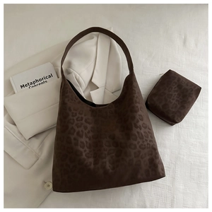 Detail of leopard print hobo bag with matching pouch on minimalist white fabric background