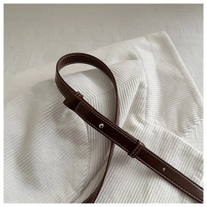 Close-up of vintage brown leather bag strap with white stitching and gold metal buckle