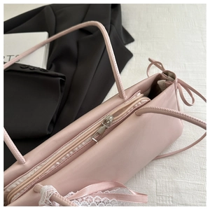 Pink shoulder bag detail showing lace lace trimming, ribbon bow, and zipper closure