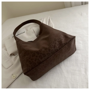 Detail view of large leopard print tote bag with matte texture on white fabric