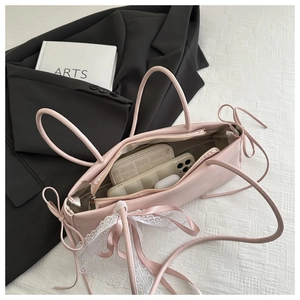 Top view of pink satin handbag interior with phone and quilted wallet on elegant tablecloth