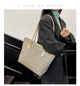 Side view of large vintage monogram tote bag worn over the shoulder with a dark blazer