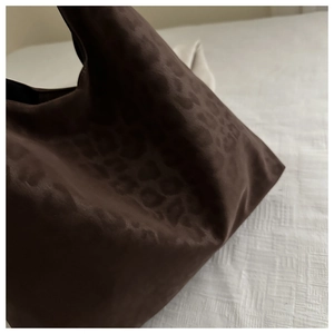 Detail of soft brown leopard print suede tote bag on white textured background