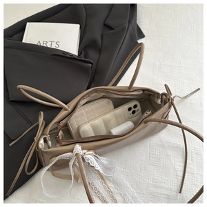 Detail of the spacious interior of a light brown baguette bag with a white lace bow