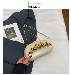 Detail view of cream leather clutch bag featuring a gold wavy metal accent and chain strap