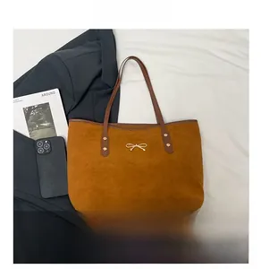 Detail show of large brown suede tote bag with golden bow and leather shoulder straps