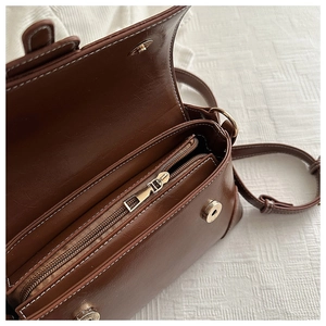 Interior view of brown faux leather bag showing three compartments and gold zipper
