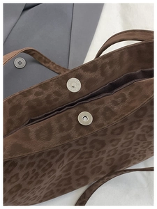 Close-up of leopard print shoulder bag with double magnetic metal buckle closures