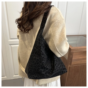 Close-up of a large black leopard print tote bag with a soft texture on a model's shoulder